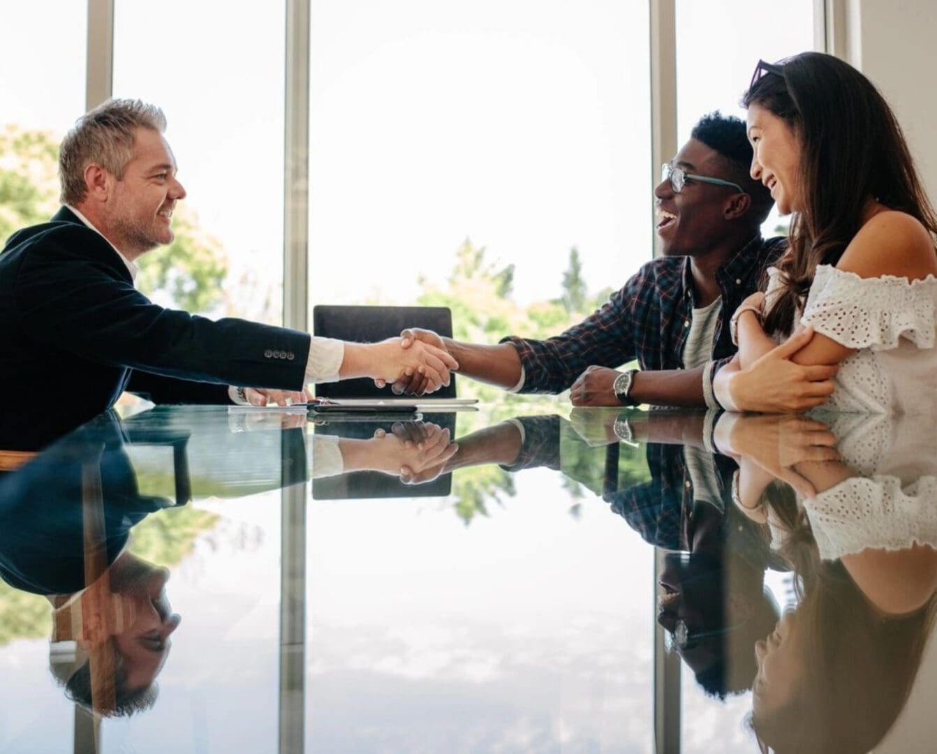 A group of people sitting around a table shaking hands.